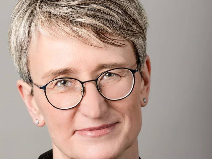 Geschäftsführerin des Theater Plauen-Zwickau in schwarzer Bluse und mit Halskette vor grauem Hintergrund.