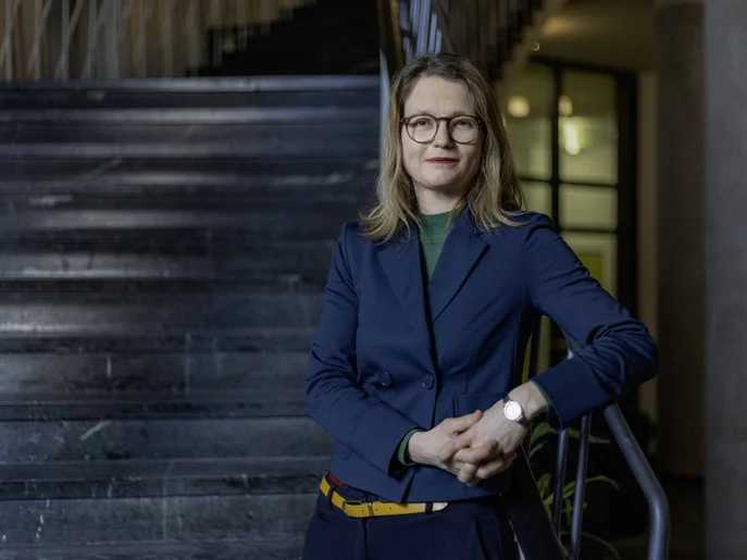 Bürgermeisterin der Stadt Dresden steht auf einer Marmortreppe mit  mit Brille und blauem Anzug.